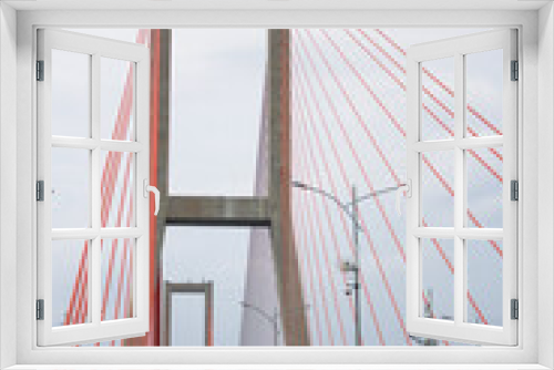 Fototapeta Naklejka Na Ścianę Okno 3D - Scene of the famous Suramadu Bridge and its red suspension steel cables with lamp post on road and cloudy sky background.