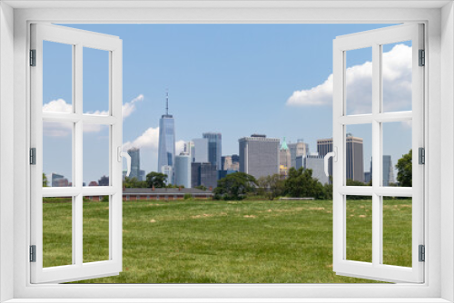 Fototapeta Naklejka Na Ścianę Okno 3D - Lower Manhattan Skyline seen from a Green Grass Field on Governors Island in New York City during the Summer