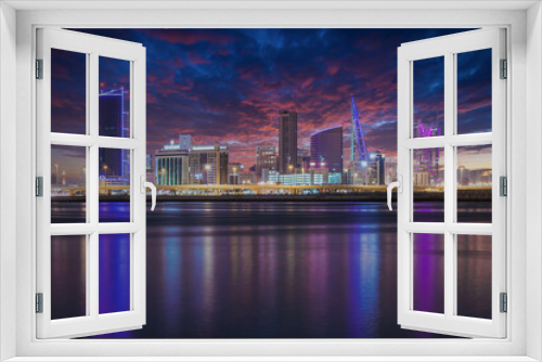 Fototapeta Naklejka Na Ścianę Okno 3D - The sun set modern city skyline with neon lights and reflection in the water. Manama, the Capital of Bahrain, Middle East