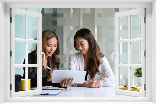 Attractive businesswoman using a digital tablet to discussing information with her colleague.