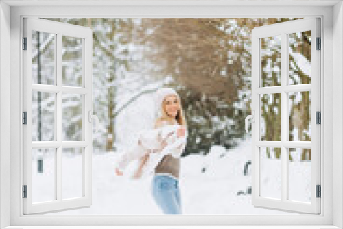 Close up portrait of an beautiful girl in a woolen sweater enjoying winter moments. Outdoors photo of a short-haired lady in a pink hat having fun on a snowy morning on a blurred nature background.