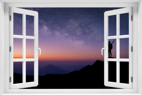 Fototapeta Naklejka Na Ścianę Okno 3D - Silhouette of young traveler with backpack standing and watched the star and milky way alone on top of the mountain. He enjoyed traveling and was successful when he reached the summit.
