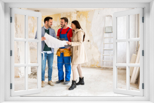 Young couple looking blueprints of their home with handyman