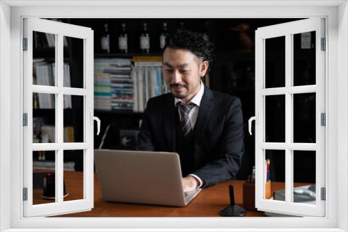 Handsome Asian (Japanese) businessman man looking down at his computer, copy space to the left.