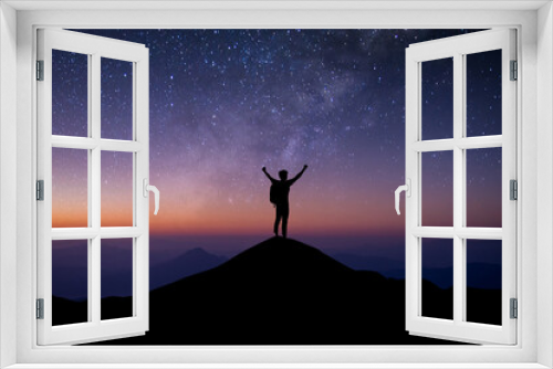 Fototapeta Naklejka Na Ścianę Okno 3D - Young traveler with backpack standing and open both arm and watched night sky view, star and milky way alone on top of the mountain. He enjoyed traveling and was successful when he reached the summit.