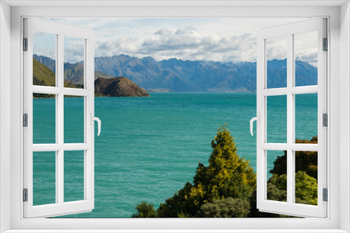Fototapeta Naklejka Na Ścianę Okno 3D - Scenic landscape view of Lake Hawea in New Zealand showing turquoise water with mountains in the background blue sky with white puffy clouds horizontal shot while on vacation holiday postcard format 