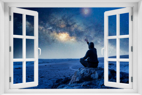 Fototapeta Naklejka Na Ścianę Okno 3D - unknown person sitting on the rock hand up under the Milky Way at night celebrating or showing amazement for the moment