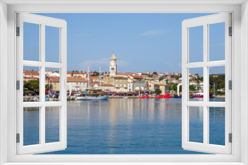 Fototapeta Naklejka Na Ścianę Okno 3D - Shore line of city center of Krk, Croatia and the port. In the back there is a church tower. Lots of yachts and submarines parked in the port. There is a forest in the back. Gloomy weather