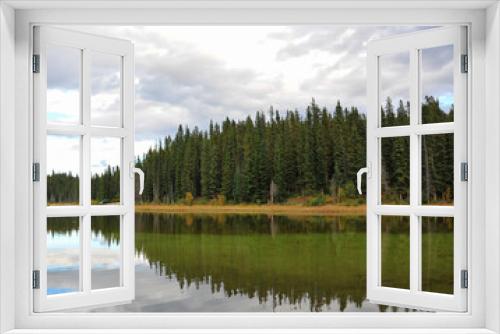 Fototapeta Naklejka Na Ścianę Okno 3D - Across the lime green lake of Goldeye campground near Nordegg, Alberta, Canada creates reflection of the pine trees