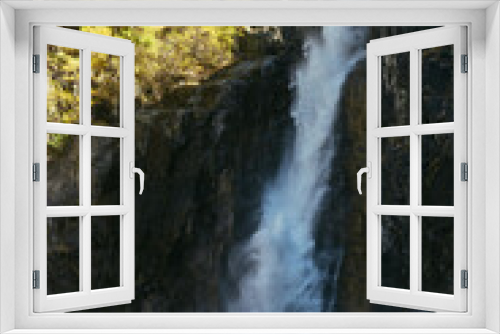 Fototapeta Naklejka Na Ścianę Okno 3D - Scenic autumn landscape with vertical big waterfall and yellow trees at mountain top in sunshine. Powerful large waterfall in rocky gorge. High falling water and trees of golden colors in fall time.