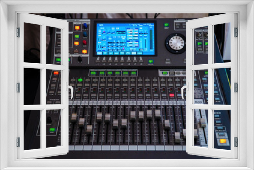 Modern digital mixing console with faders, control buttons and touch screen. Selective focus