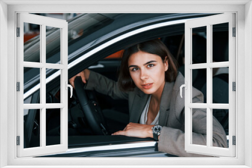 Woman testing new car. Sitting indoors in modern automobile