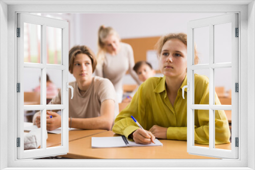 Portrait of teenage school girl and boy sitting together in classroom during lesson in secondary school