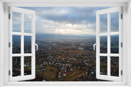 Fototapeta Naklejka Na Ścianę Okno 3D - Aerial view of rural homes and distant high rise apartment buildings in city residential area during cloudy weather