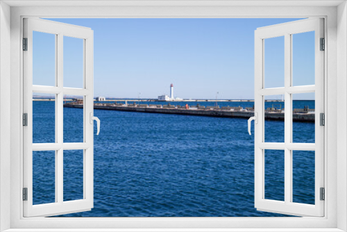 Fototapeta Naklejka Na Ścianę Okno 3D - a seaport on the seashore, a lighthouse is visible in the distance, a beautiful blue sea