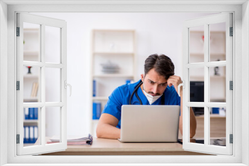 Young male doctor working in the clinic during pandemic