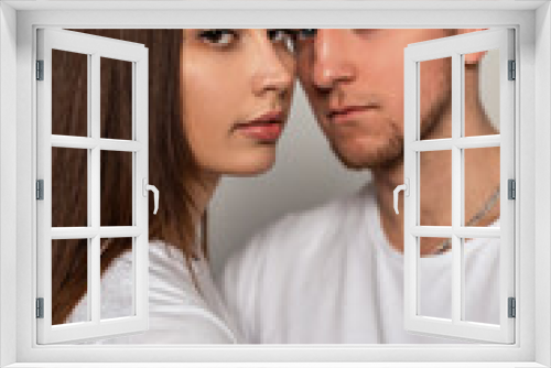 Beautiful young couple in stylish classic white t-shirts in the studio. Pretty woman and a handsome man with a haircut in fashionable clothes in the studio.