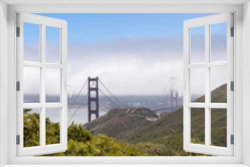 Fototapeta Naklejka Na Ścianę Okno 3D - The Golden Gate Bridge with haze and fog in the Bay, seen through trees and foliage. (selective focus)