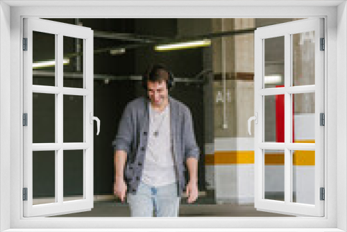 portrait of fashionable cool man on an industrial environment listening to music with earphones. vertical shot. High quality photo