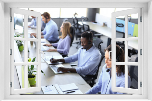 Young employee working with a headset and accompanied by her team