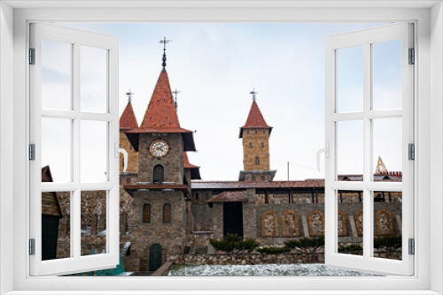 Fototapeta Naklejka Na Ścianę Okno 3D - Part of the fortress wall of the castle, with a tower and a large clock tower. Architecture of one of the districts of the Rostov region of the Russian Federation.