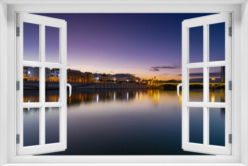 Fototapeta Naklejka Na Ścianę Okno 3D - Sunset over the river Guadalquivir in downtown Seville with amazing colors in the sky and a view on the riverside of  the Triana neighbourhood.