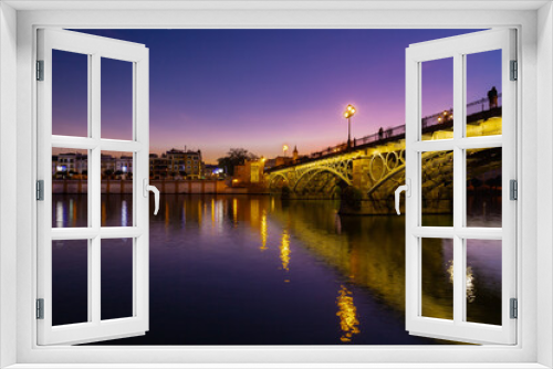 Fototapeta Naklejka Na Ścianę Okno 3D - Sunset over the river Guadalquivir in downtown Seville with amazing colors in the sky and a view on the riverside of  the Triana neighbourhood.
