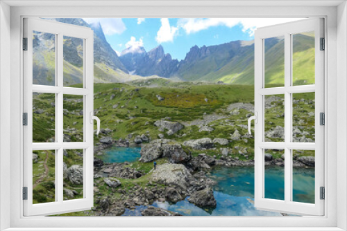 Fototapeta Naklejka Na Ścianę Okno 3D - A man enjoying the Colorful Abudelauri mountain lakes in the Greater Caucasus Mountain Range in Georgia,Kazbegi Region. Trekking and outdoor travel.Alpine pastures.Lake Reflection.Green lake