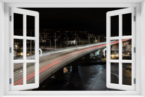 Fototapeta Naklejka Na Ścianę Okno 3D - Cars and trucks driving at night over a bridge on a higly trafficated road in the middle of a city over a river