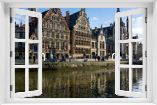 Fototapeta Naklejka Na Ścianę Okno 3D - Panoramic of Ghent next to the water channels, with the reflection of the buildings in the water, on a sunny day.