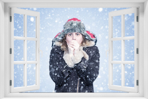 Frozen young girl in winter clothes warms her hands, cold, snow, frost, blizzard