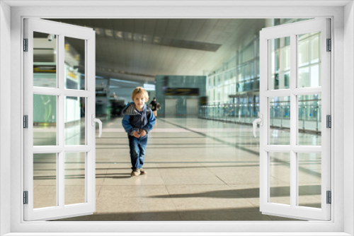 Cute  baby boy waiting boarding to flight in airport transit hall near departure gate. Active family lifestyle travel by air with children