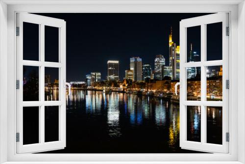 Fototapeta Naklejka Na Ścianę Okno 3D - Skyline Frankfurt am Main mit Blick auf den Main von einer Brücke aus. Die Lichter der Büros spiegeln sich auf der Wasseroberfläche. 