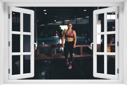Sport and cardio training idea for keeping healthy lifestyle, full length portrait of cheerful female bodybuilder in tracksuit smiling at camera - ready for pilates exercising in modern gym hall