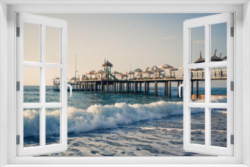 Fototapeta Naklejka Na Ścianę Okno 3D - View of the beach and the Mediterranean Sea, beautiful clear sea water on a warm sunny day. The concept of rest in a warm country. Wooden pier that stands on the water