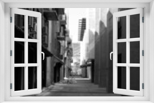 Fototapeta Naklejka Na Ścianę Okno 3D - Alley in a monotone high-rise building, black and white