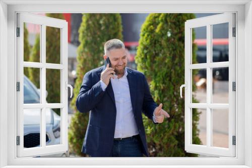 Young happy businessman calling phone near business centre