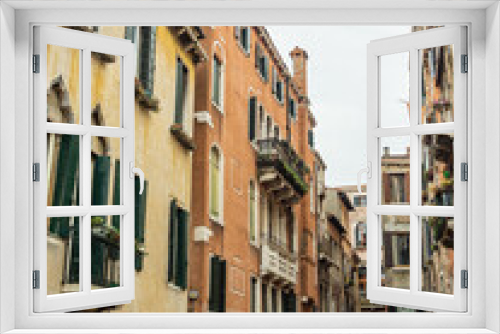 Fototapeta Naklejka Na Ścianę Okno 3D - A quiet, empty Venetian street with beautiful pastel colored buildings taken during the winter on an overcast day - Venice, Italy.