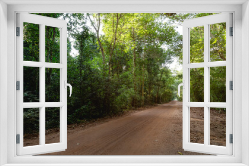 Fototapeta Naklejka Na Ścianę Okno 3D - Dirt road stretching through jungle at rural. Thailand