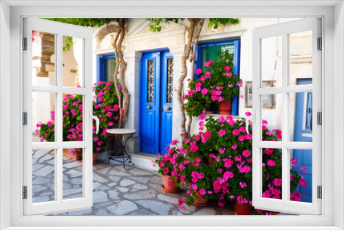 Fototapeta Naklejka Na Ścianę Okno 3D - One of the charms of Pyrgos, a famous village of marble craftsmen in Tinos, in the Cyclades, in the heart of the Aegean Sea, are the narrow cobbled streets with white houses and flowers