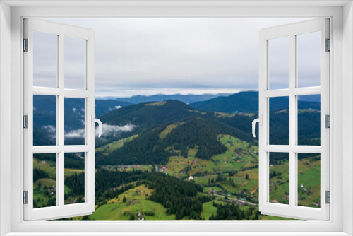 Fototapeta Naklejka Na Ścianę Okno 3D - Green slopes of Ukrainian Carpathian mountains in summer. Cloudy morning, low clouds. Aerial drone view.