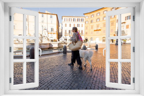 Style woman walks with italian shepherd dog on Navona square in Rome on a sunny day. Italian lifestyle and street fashion concept