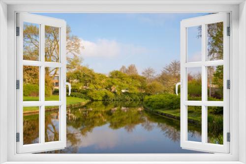 Fototapeta Naklejka Na Ścianę Okno 3D - Beautiful spring landscape of park trees located along the bank of the canal with reflection of trees and blue sky in the water