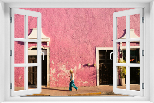 Fototapeta Naklejka Na Ścianę Okno 3D - Bright texture shaby pink wall. pedestrian in blue clothes walks along sidewalk. Colors of mexican street city valladolid