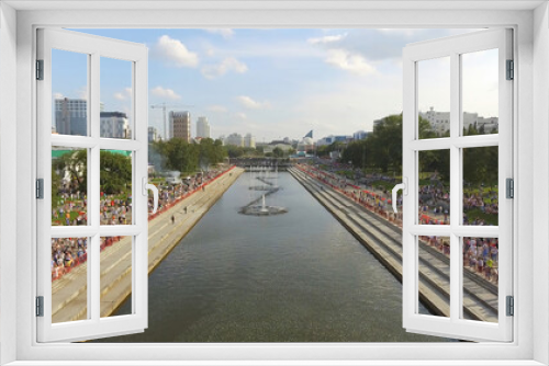 Fototapeta Naklejka Na Ścianę Okno 3D - Aerial view of plenty of people walking on the embankment with fountains in warm summer day against the blue cloudy sky. Action. Summer life of the big city