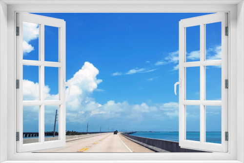 Fototapeta Naklejka Na Ścianę Okno 3D - Empty highway in Miami in clear weather with lots of white fluffy clouds and ocean views. Florida's summer road across the bridge with a balanced flow of cars