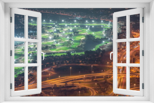 Fototapeta Naklejka Na Ścianę Okno 3D - Aerial view to Golf course with green lawn and lakes, villas and houses behind it night timelapse.