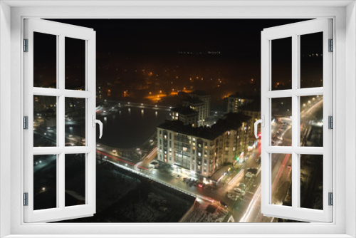 Fototapeta Naklejka Na Ścianę Okno 3D - Aerial view of high rise apartment buildings and bright illuminated streets in city residential area at night. Dark urban landscape
