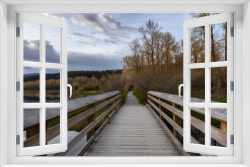 Fototapeta Naklejka Na Ścianę Okno 3D - View of a Wooden Path with green fresh trees in Shoreline Trail, Port Moody, Greater Vancouver, British Columbia, Canada. Trail in a Modern City during a Sunny Spring Sunset.