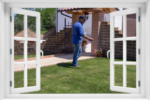 Fototapeta Naklejka Na Ścianę Okno 3D - Photo of a gardener who manually fertilizes the lawn in his home garden